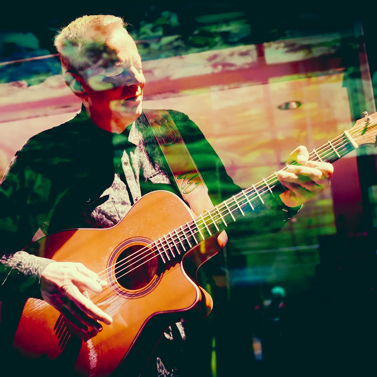 Artistic, promotional photo of Tommy Emmanuel, CGP, playing acoustic guitar.