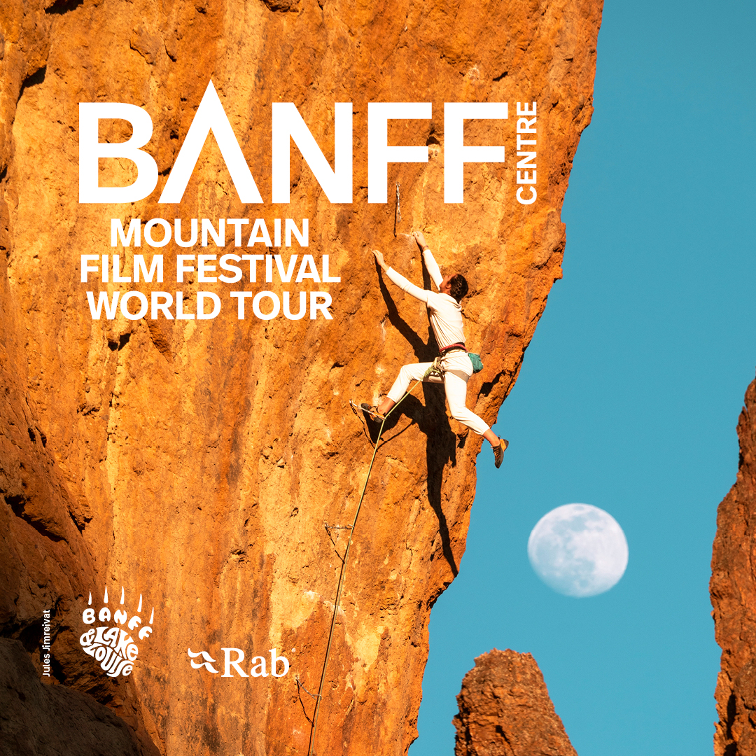 The Banff Mountain Film Festival logo over a photo of a rock climber hanging from an orange colored cliff face, with a blue sky and almost full moon in the background.