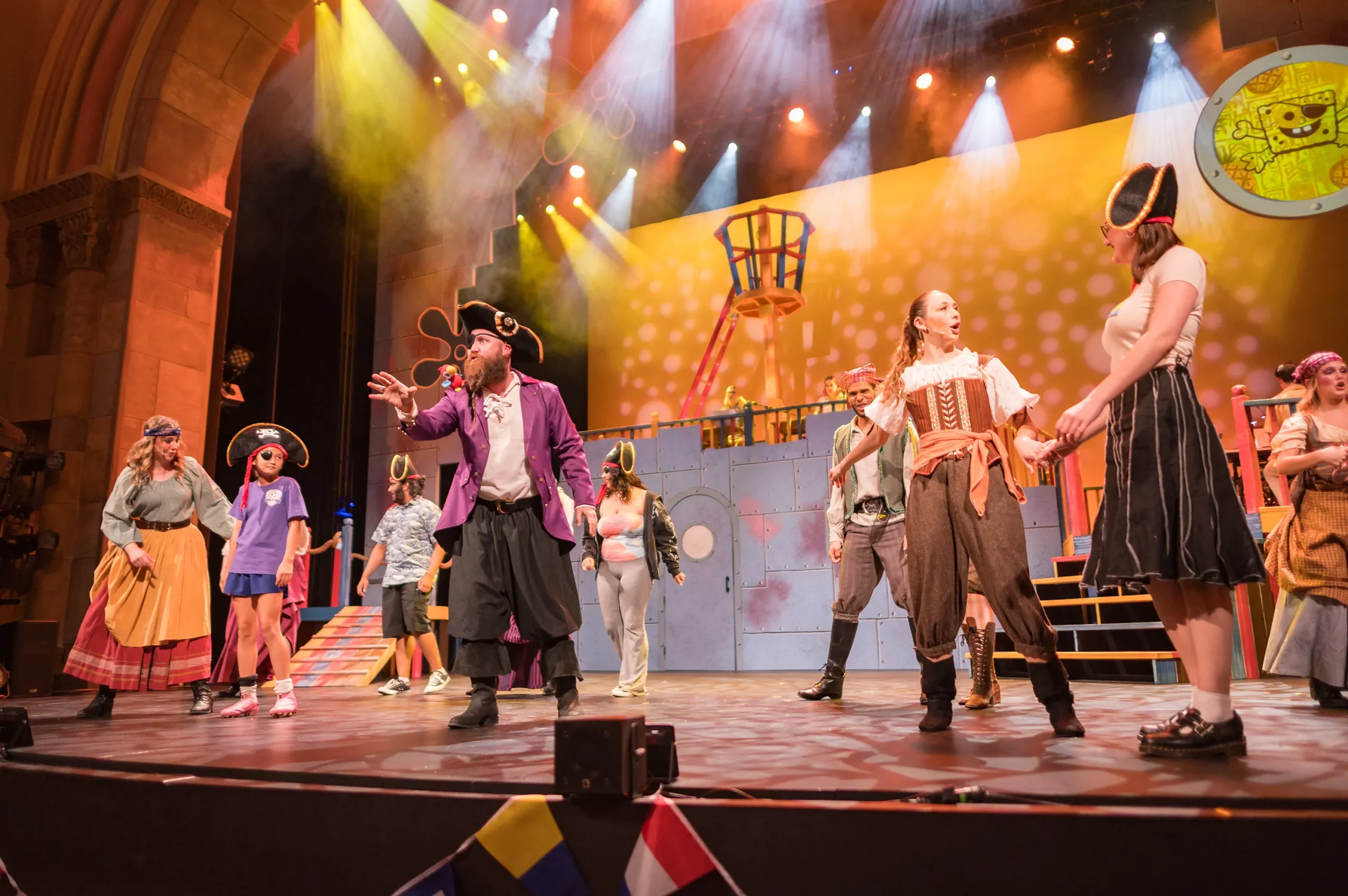 The cast of SpongeBob SquarePants: The Musical performs on stage alongside student volunteers.