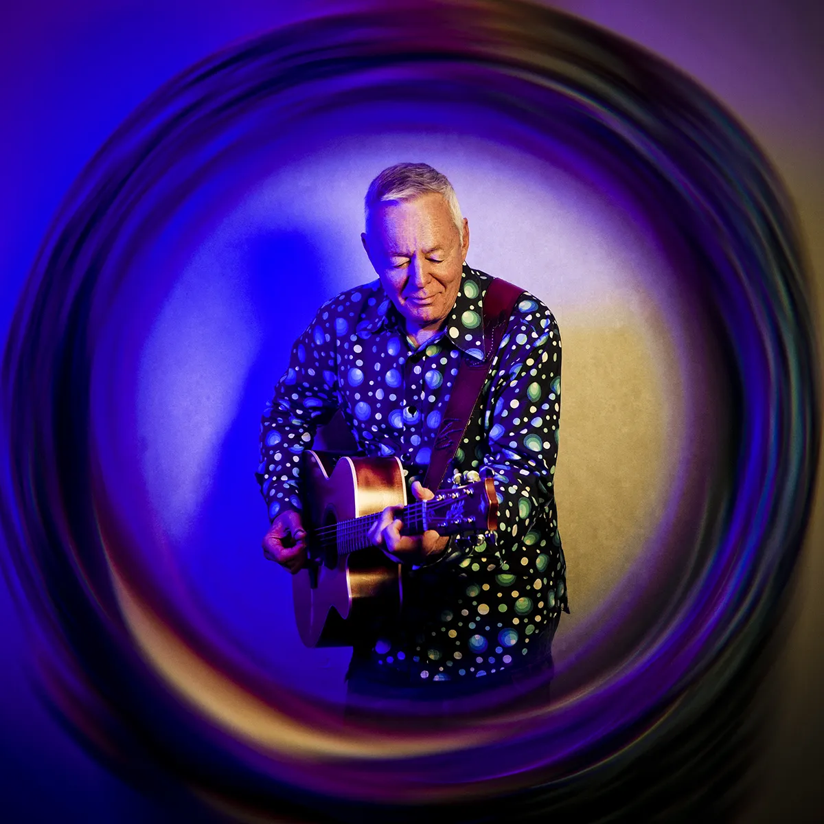 Tommy Emmanuel, CPG, in an artistic, blue-hued photograph.